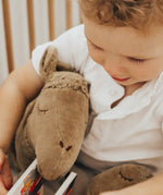 A toddler cuddling the organic cotton stuffed camel toy from Senger