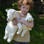 A child cuddling a Senger large and small cuddly polar bear soft toy in their arms.