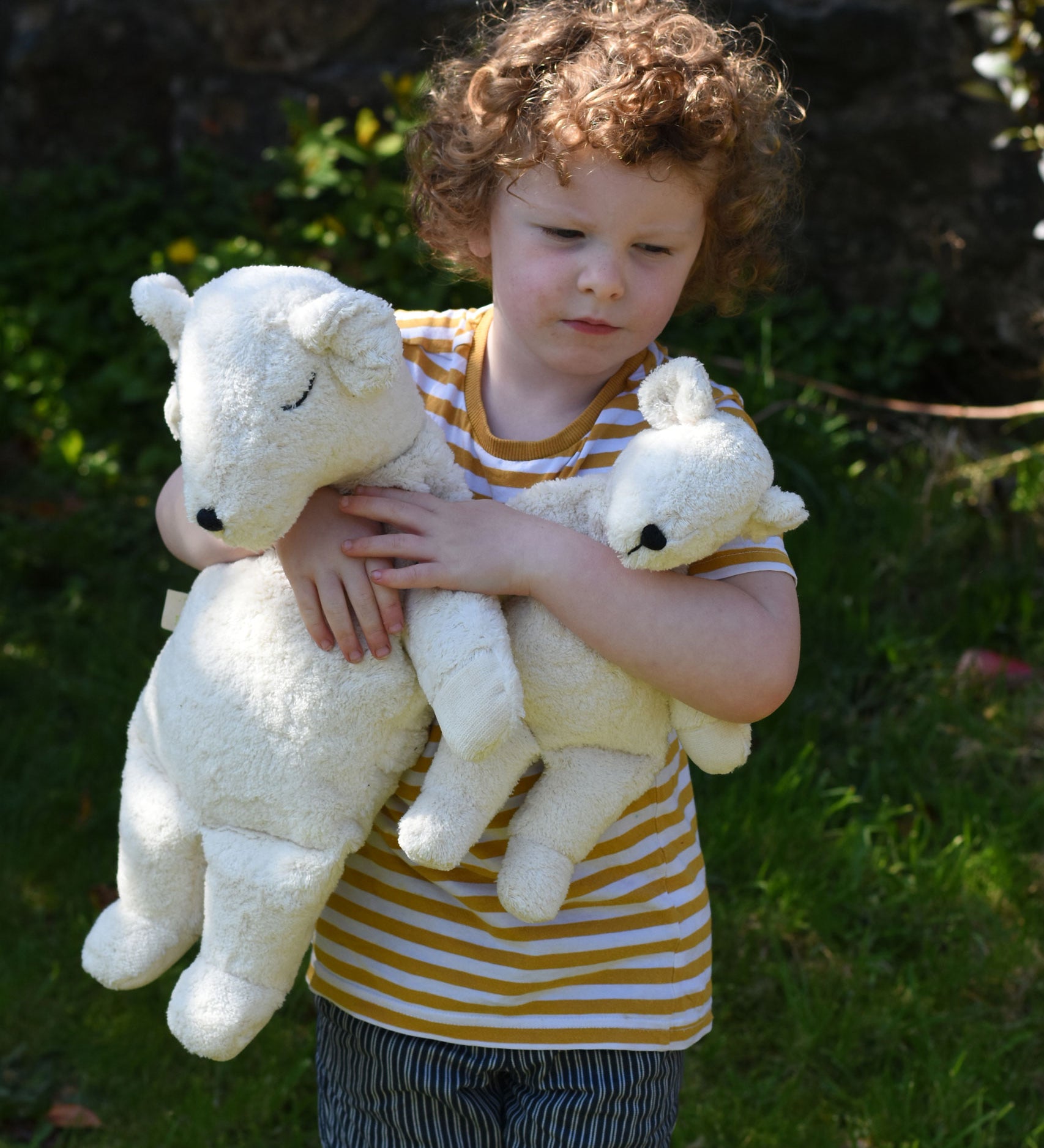 A child cuddling a Senger large and small cuddly polar bear soft toy in their arms.