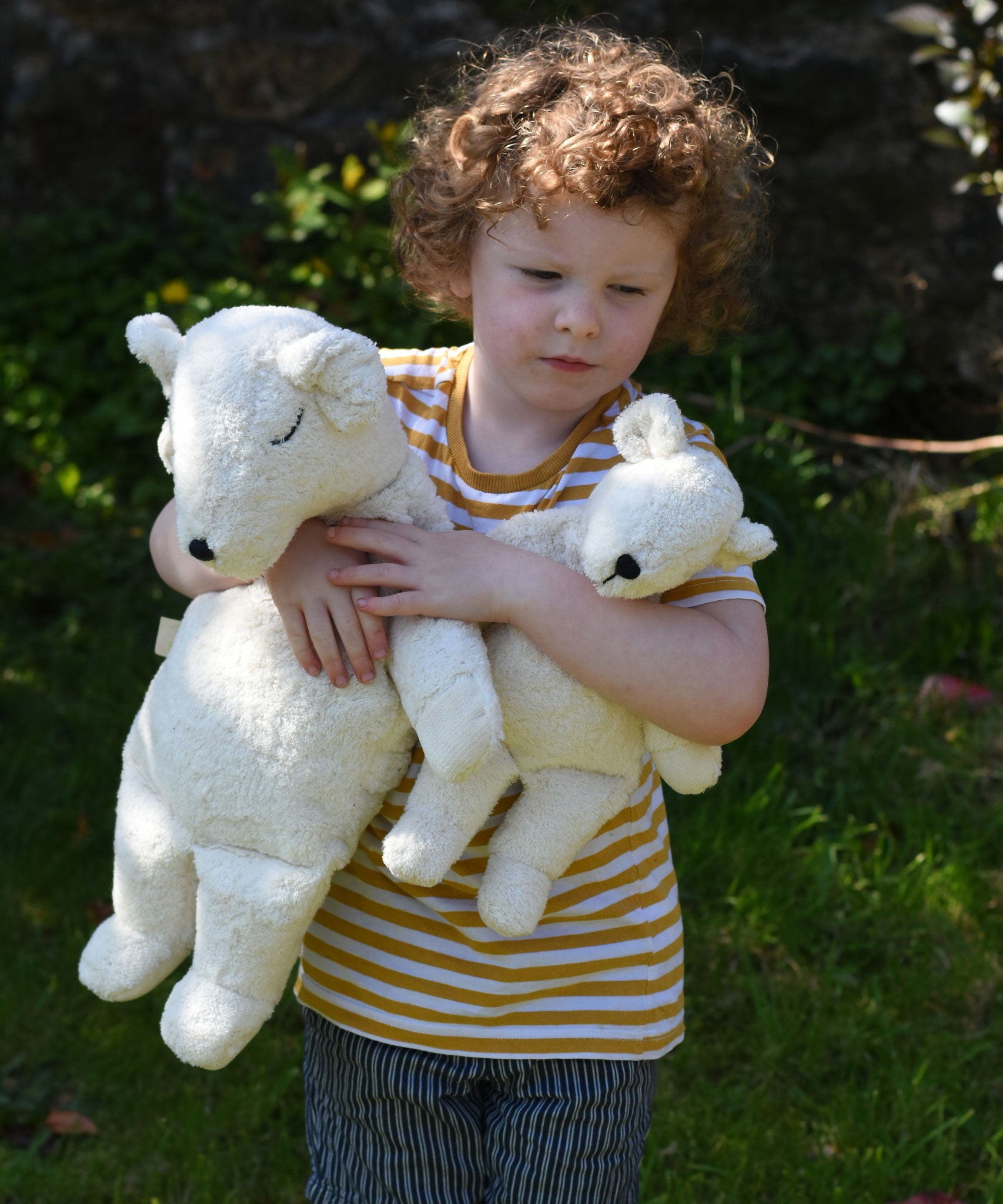 A child cuddling a Senger large and small cuddly polar bear soft toy in their arms.