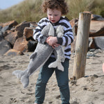 A child holding the large and small Senger cuddly whale animal soft toys with one in each arm.