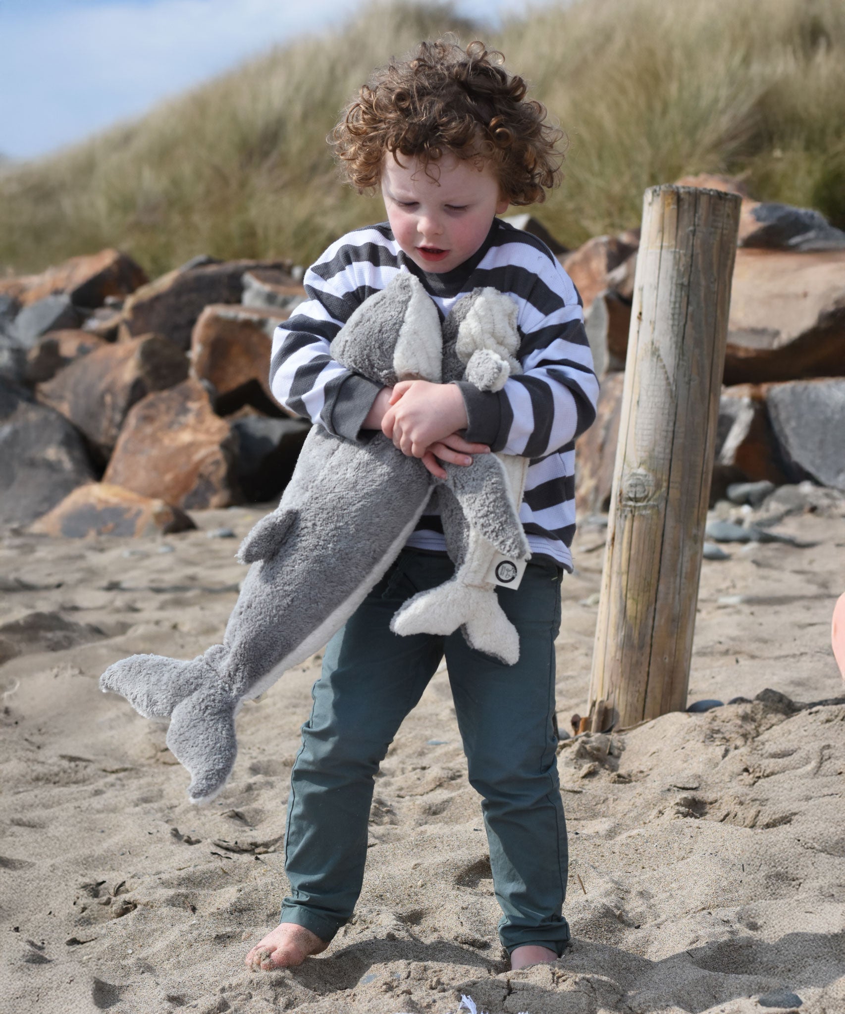 A child holding the large and small Senger cuddly whale animal soft toys with one in each arm.