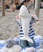 A child holding the large Senger cuddly whale soft toy up showing the whale's white underside.