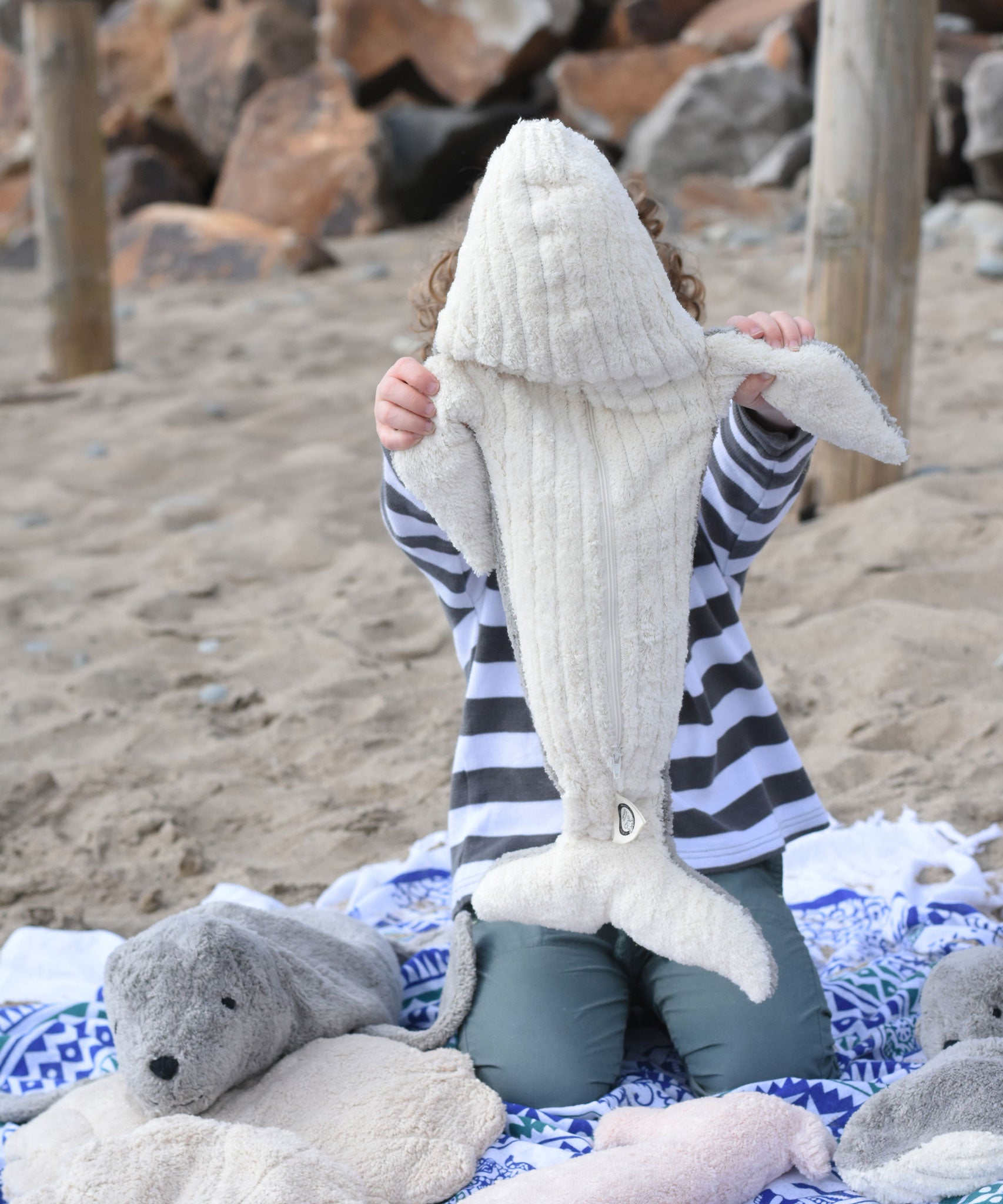 A child holding the large Senger cuddly whale soft toy up showing the whale's white underside.