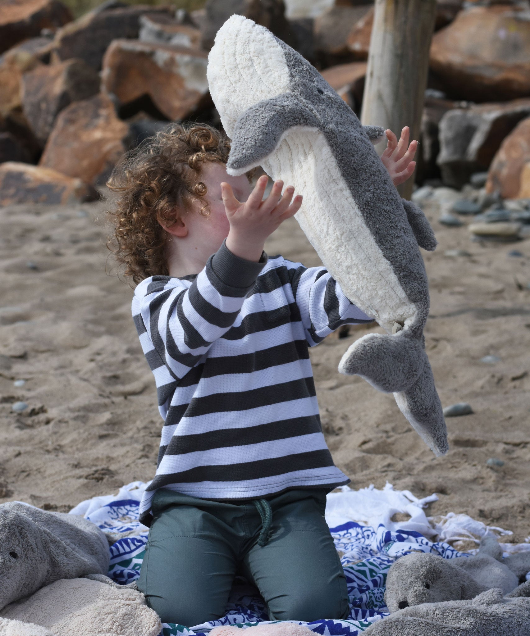 A child throwing the large Senger cuddly whale soft toy into the air.