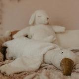 A Senger large white cuddly goose soft toy lying flat on a blanket with a sheep soft toy in the background