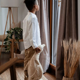 Child standing next to a large cream Senger cuddly goose soft toy and holding it's head in a living room 