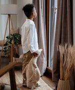 Child standing next to a large cream Senger cuddly goose soft toy and holding it's head in a living room 
