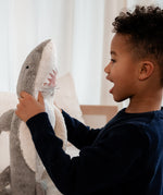 Child interacting with the Senger Naturwelt Large Cuddly Shark, organic heatable soft toy made from GOTS cotton plush and natural wool.