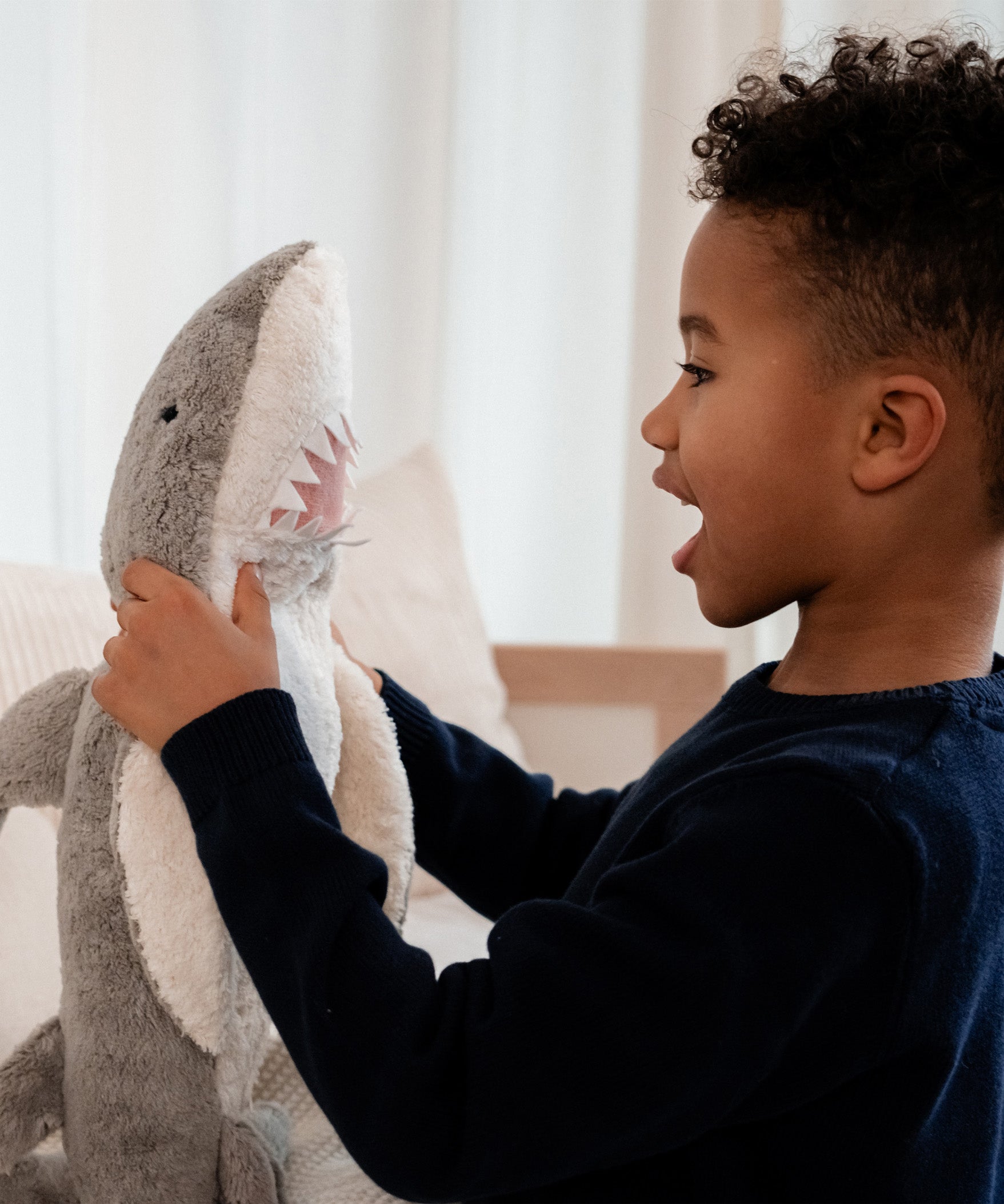 Child interacting with the Senger Naturwelt Large Cuddly Shark, organic heatable soft toy made from GOTS cotton plush and natural wool.