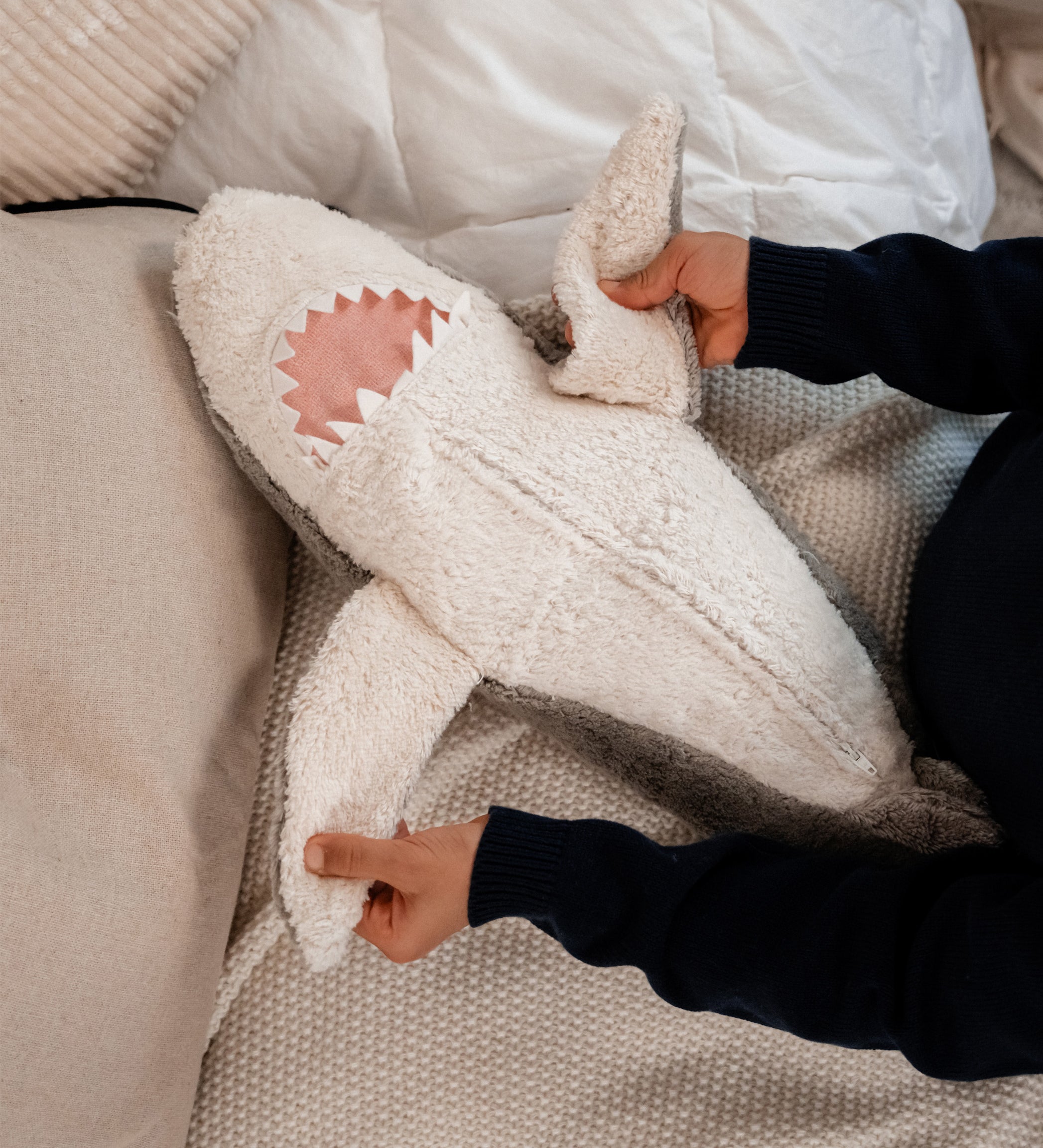 hands holding the Senger Naturwelt Large Cuddly Shark, organic GOTS cotton plush soft toy with removable spelt husk heat cushion.