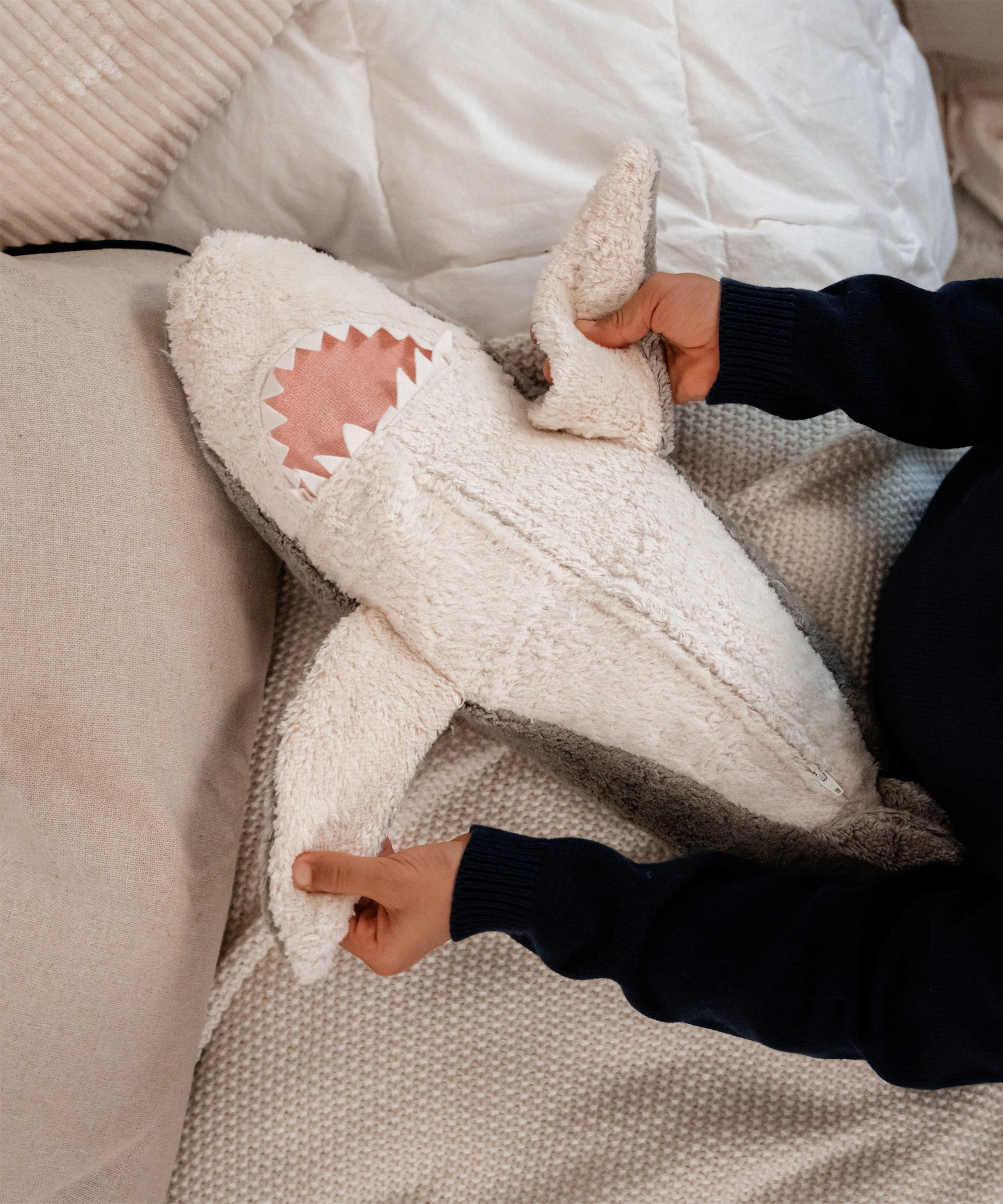 hands holding the Senger Naturwelt Large Cuddly Shark, organic GOTS cotton plush soft toy with removable spelt husk heat cushion.