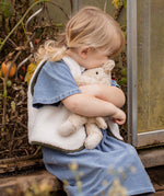 Child cuddling the Senger Naturwelt Small Cuddly Bear in Linen, organic heatable bear with removable cherry stone cushion.