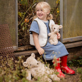 Child smiling while holding the Senger Naturwelt Small Cuddly Bear in Linen beside the larger Linen bear, organic heatable soft toys.
