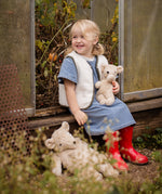 Child smiling while holding the Senger Naturwelt Small Cuddly Bear in Linen beside the larger Linen bear, organic heatable soft toys.