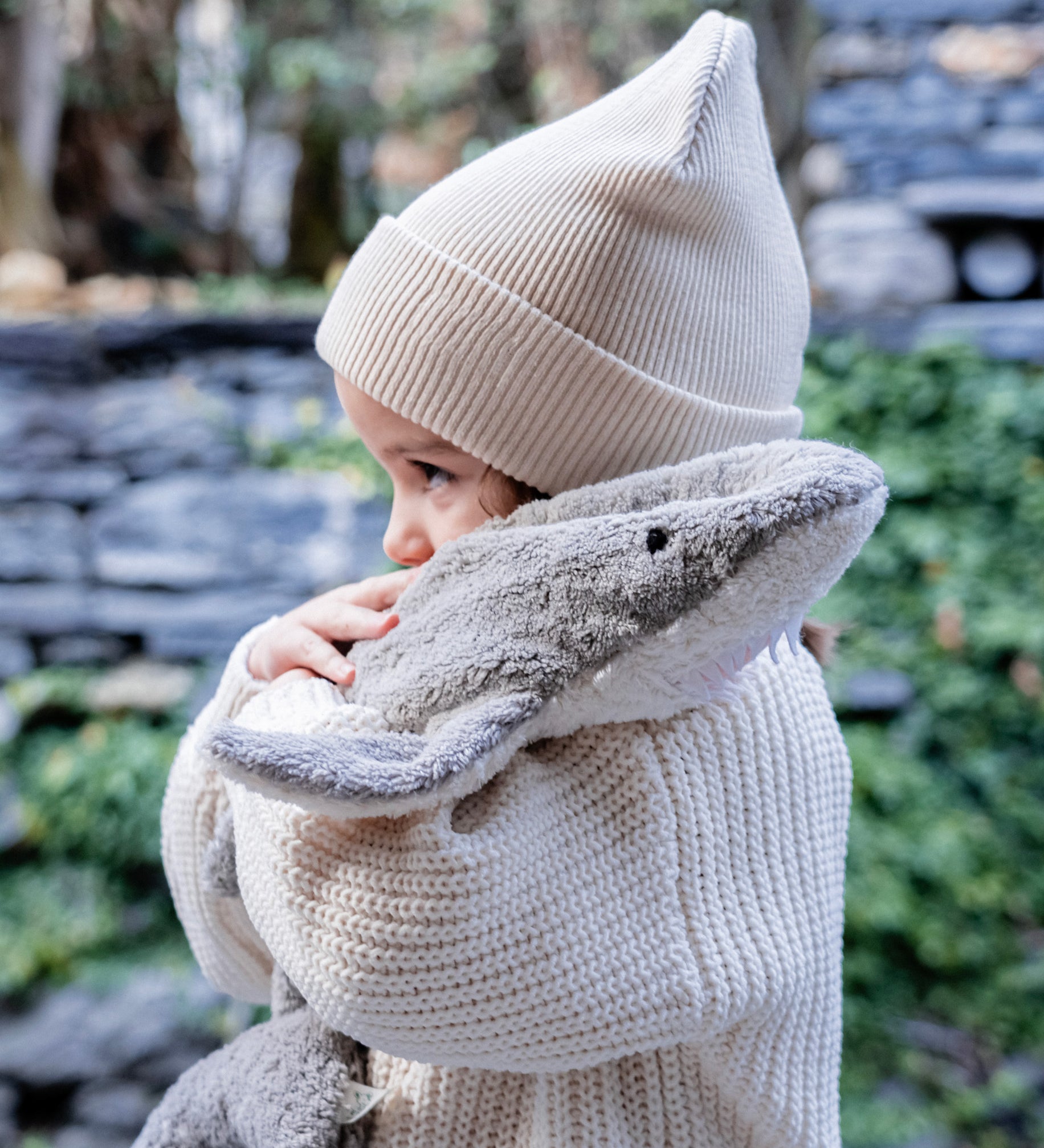 Child hugging the Senger Naturwelt Small Cuddly Shark, organic GOTS cotton plush soft toy with removable heat cushion.