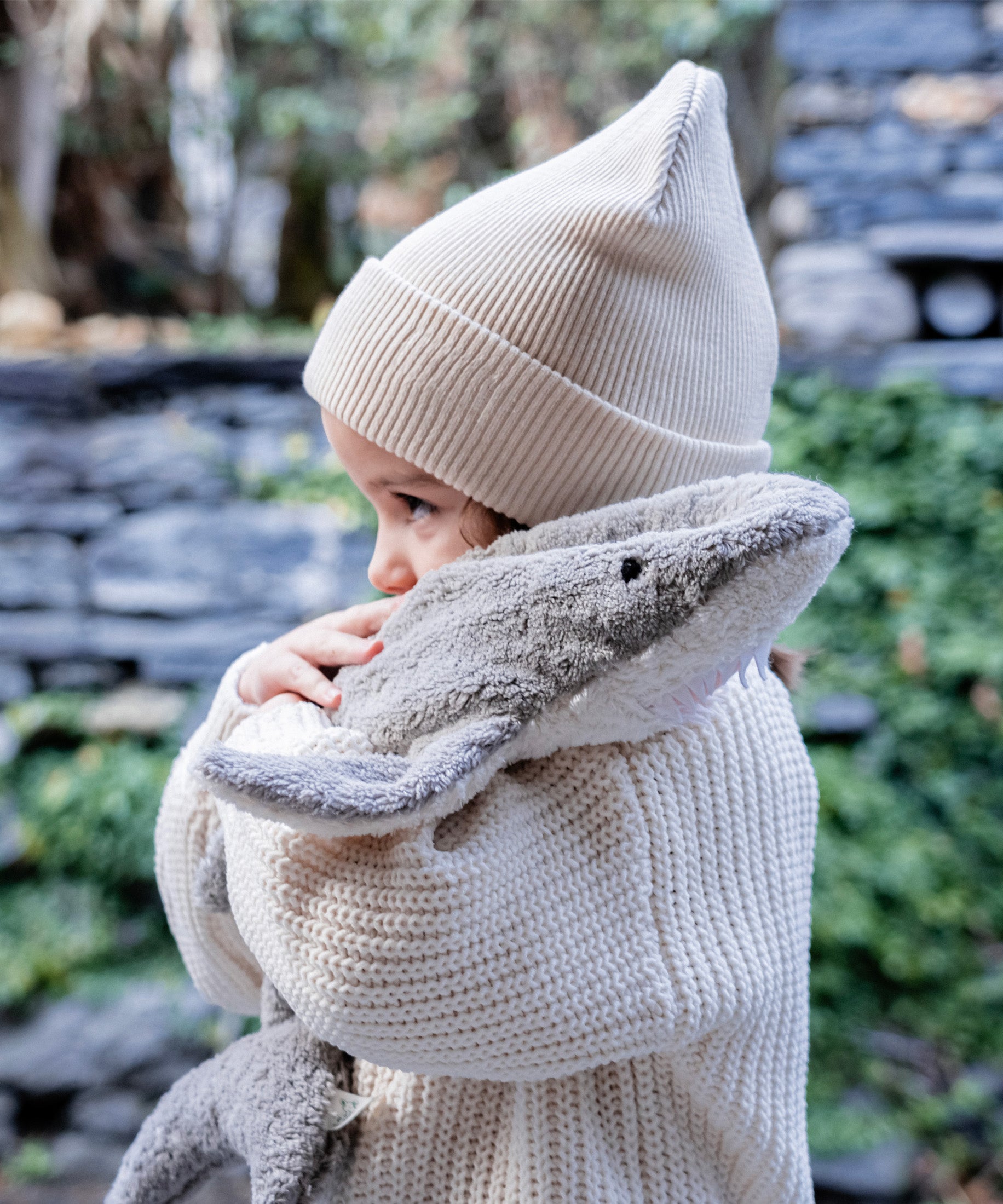 Child hugging the Senger Naturwelt Small Cuddly Shark, organic GOTS cotton plush soft toy with removable heat cushion.