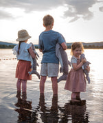 Children standing in shallow water holding the Senger Naturwelt Cuddly Shark, organic GOTS cotton heatable soft toy.