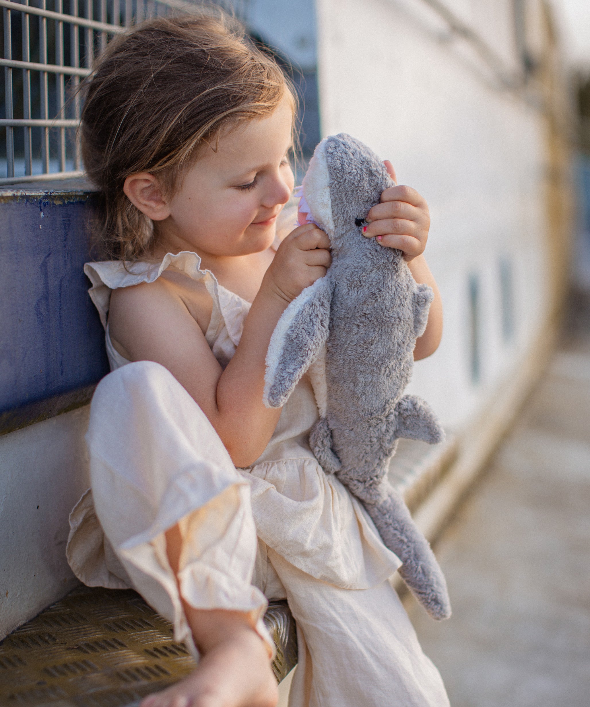 Child playing outdoors with the Senger Naturwelt Small Cuddly Shark, organic soft toy made from GOTS cotton plush and natural wool.