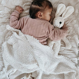 A baby sleeping and cuddling a Senger organic cotton floppy bunny rabbit soft toy