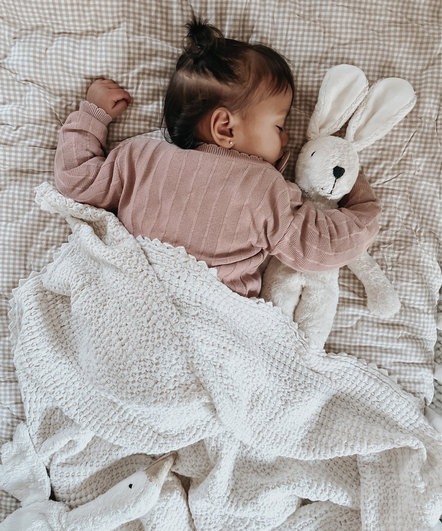 A baby sleeping and cuddling a Senger organic cotton floppy bunny rabbit soft toy