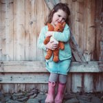A little girl cuddling the Senger organic cotton small squirrel stuffed soft toy