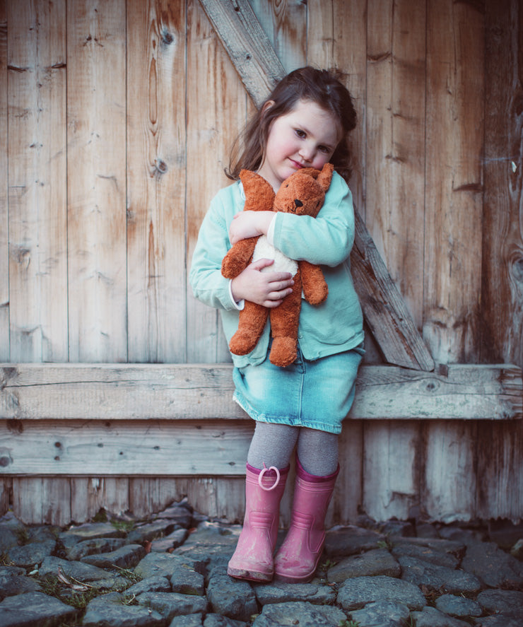 A little girl cuddling the Senger organic cotton small squirrel stuffed soft toy
