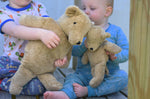 A close up of the large and small Senger beige cuddly bears in children's hands.