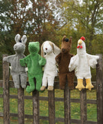 A collection of Senger hand puppets placed on a wooden fence. A donkey, frog, dog horse and chicken.