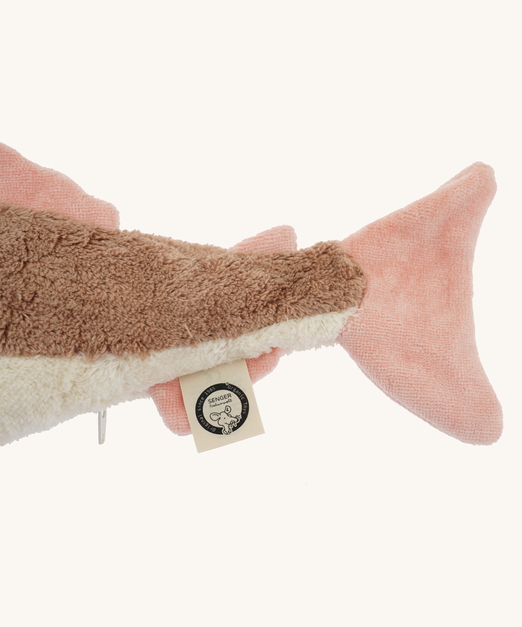 A closeup of the Senger organic cotton pink fish toy's tail and label