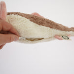 A hand unzipping the belly of the Senger organic cotton cuddly stuffed toy, to take out the heating bag from inside