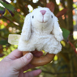 A Senger sheep baby grasping toy being help up in an adult's hand.