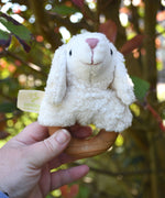 A Senger sheep baby grasping toy being help up in an adult's hand.