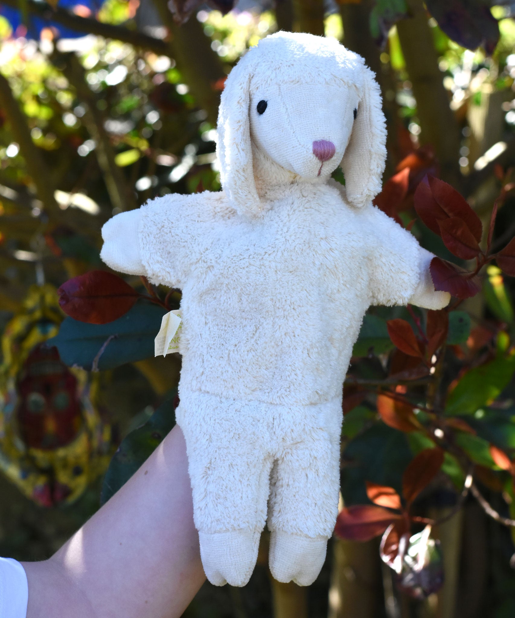 A Senger white sheep organic cotton puppet in use on a child's hand.