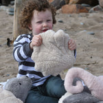 A child holding up a small Senger cuddly shell soft toy in front of them.