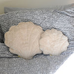 A large and small Senger shell cuddly animal soft toy placed on a grey and white coloured bed sheet.
