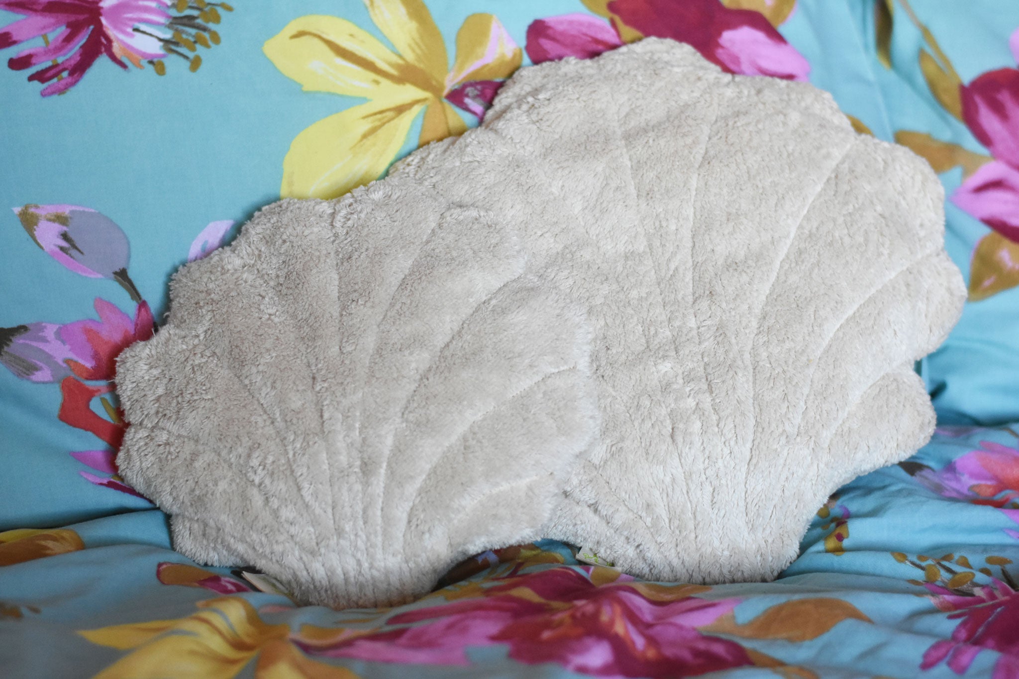 A large and small Senger shell cuddly animal soft toy placed on a colourful floral pattered bed sheet.