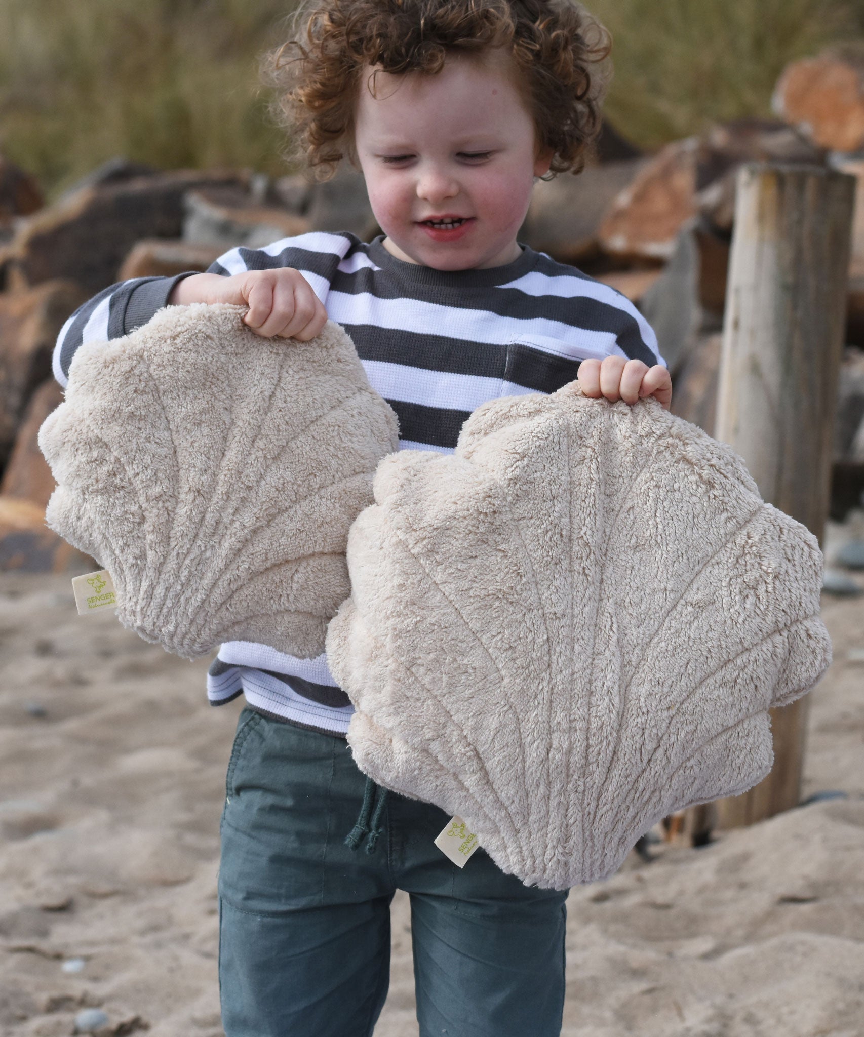 A child holding up a large and small Senger cuddly shell toy. 