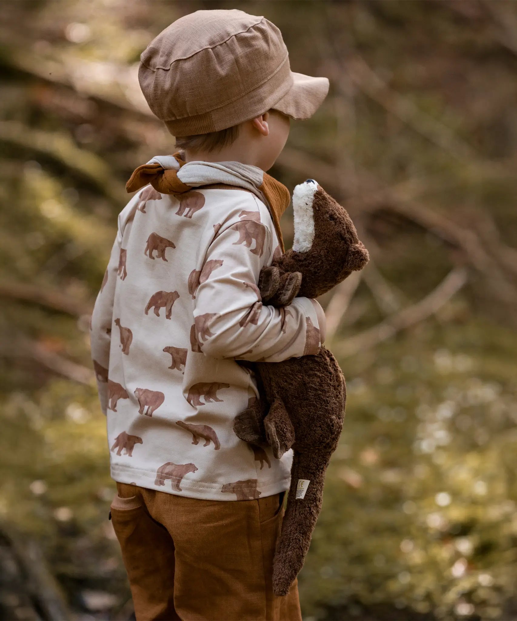 Child holding to a small brown Senger otter cuddly toy in a forest