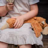 A close up of a Senger Small Cuddly Goose organic soft toy in a dark orange Rust colour on a child's lap. These soft toys are created from the highest quality, sustainable and traceable natural materials. Senger cuddly animal toys and soft dolls are handmade in Germany with love and attention to detail and we are proud Senger stockists here at Babipur. 