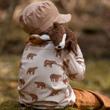 Child with a  small brown Senger otter cuddly toy on their shoulder and sitting on a rock