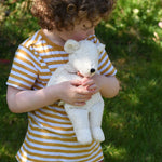 A child cuddling the small Senger polar bear soft toy in their arms.