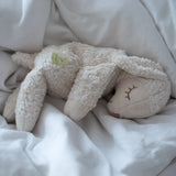 A Senger small cuddly white sheep toy sitting on lying flat on a blanket