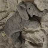 Small Senger elephant cuddly toy lying flat on a striped blanket