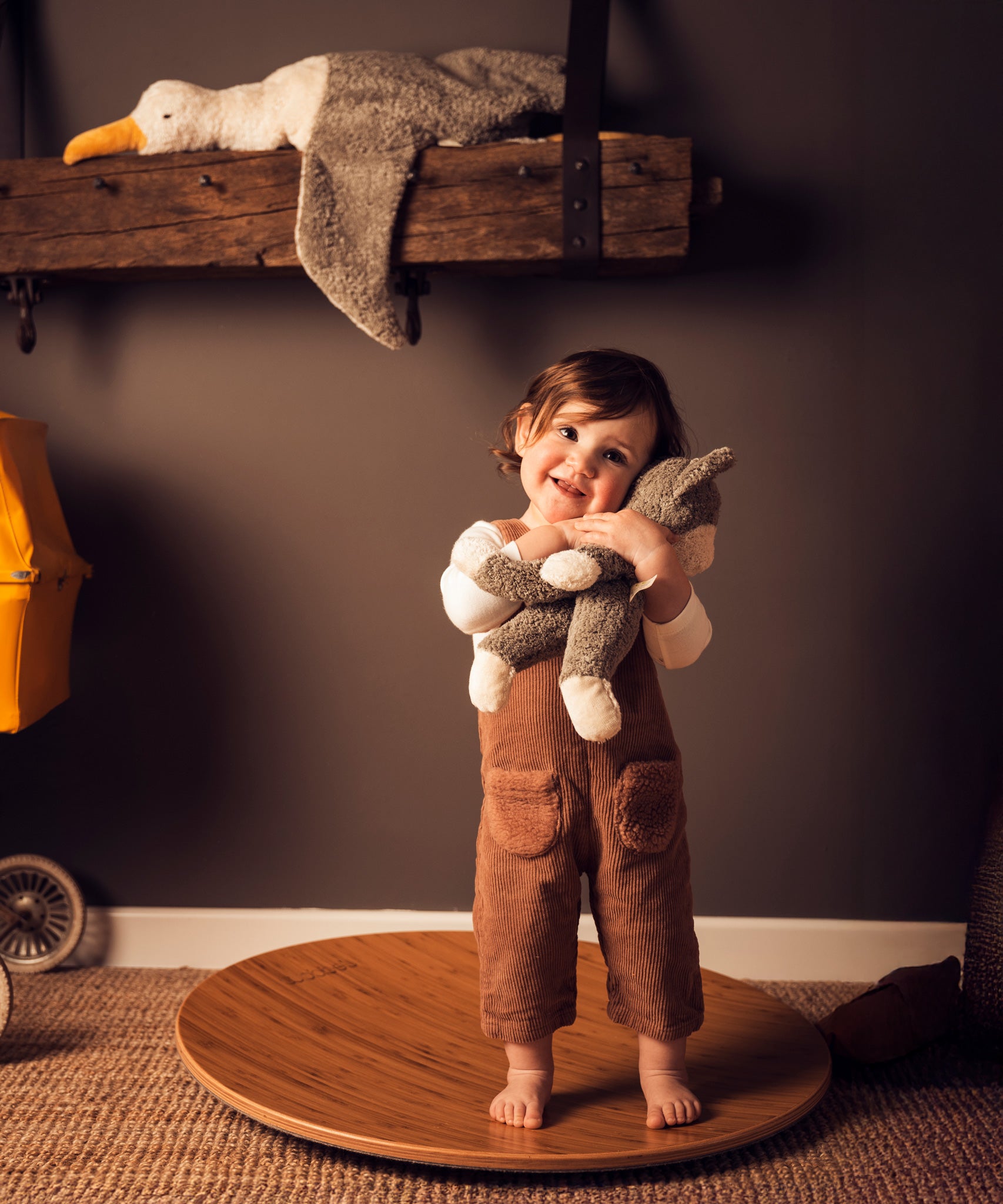 A child standing on a Wobbel 360 cuddling a Senger Small Floppy Cat.