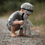 A small child bent down, playing with the Senger organic cotton stuffed floppy donkey toy. 