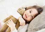 A chlld laying down cuddling a Senger Small Floppy Horse.