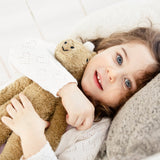 A chlld laying down cuddling a Senger Small Floppy Horse.