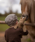 A child holding up  Senger Small Floppy Horse on their shoulder.