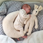 A small baby laying next to a white Senger Small Floppy Rabbit.